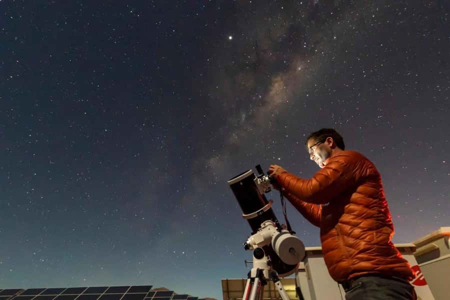 A guide at a telescope under the Milky Way in the Atacama